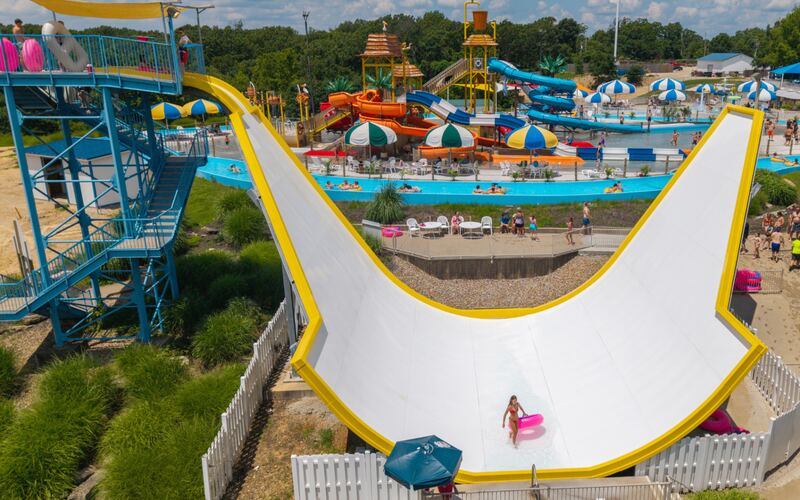 Rider on a pink tube swinging up the white and yellow Hawaiian Halfpipe water slide