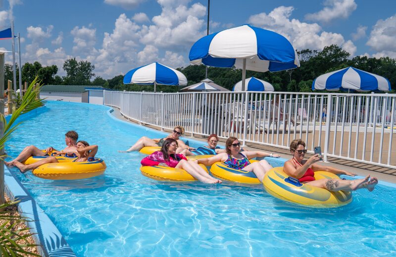Guests floating on yellow tubes down the SuperSplash USA lazy river under blue and white umbrellas