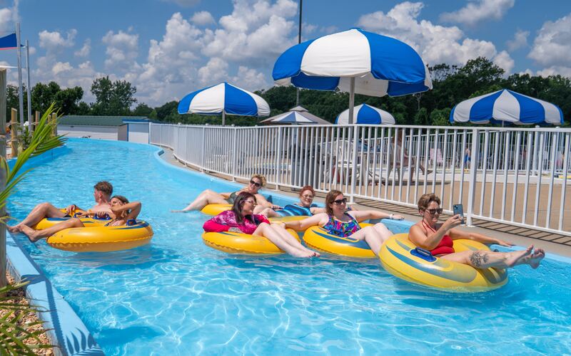 Group of guests floating on yellow tubes down the SuperSplash USA lazy river under blue and white umbrellas